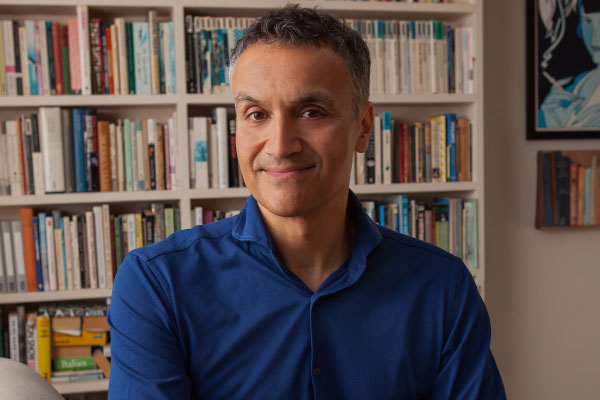 A man, Carl Honore, sitting in front of a bookcase
