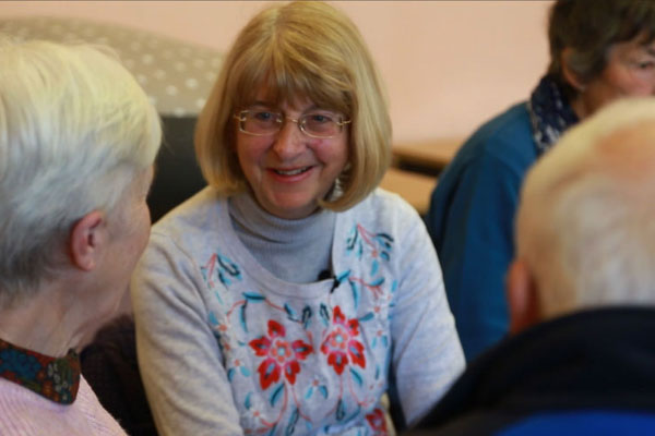 A blonde woman sitting in the centre of a group smiling