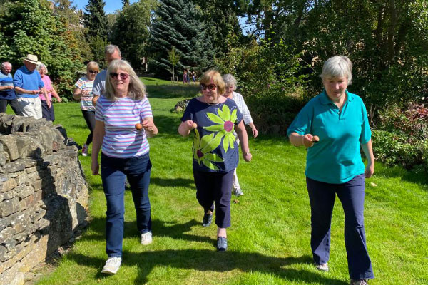 Three women walking holding eggs in spoons, on a beautiful sunny day