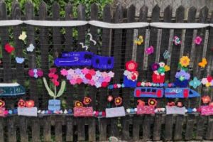 knitted trains attached to a fence