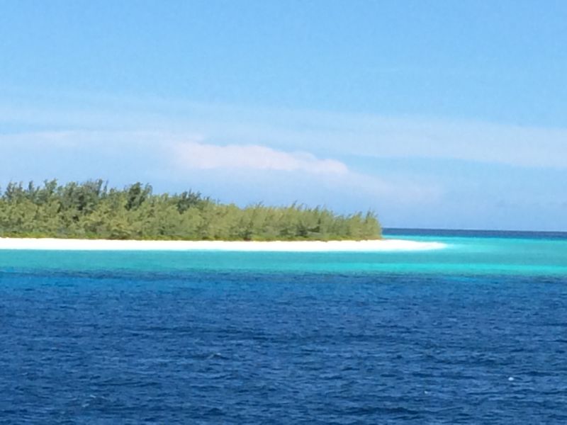 blue sea and sky with island and white sand in the middle