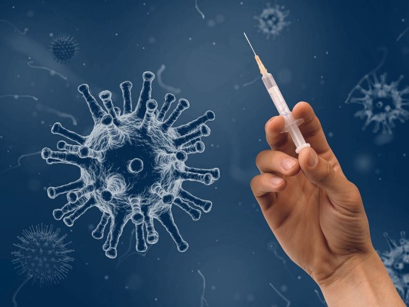 Graphic of a virus and a hand holing a vaccine syringe
