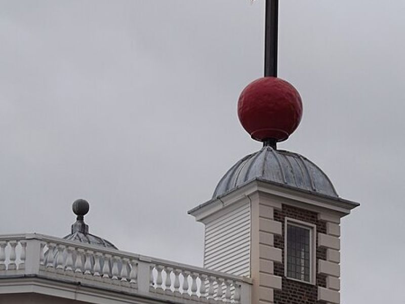a red ball on top of a tower of a building with a spire above it