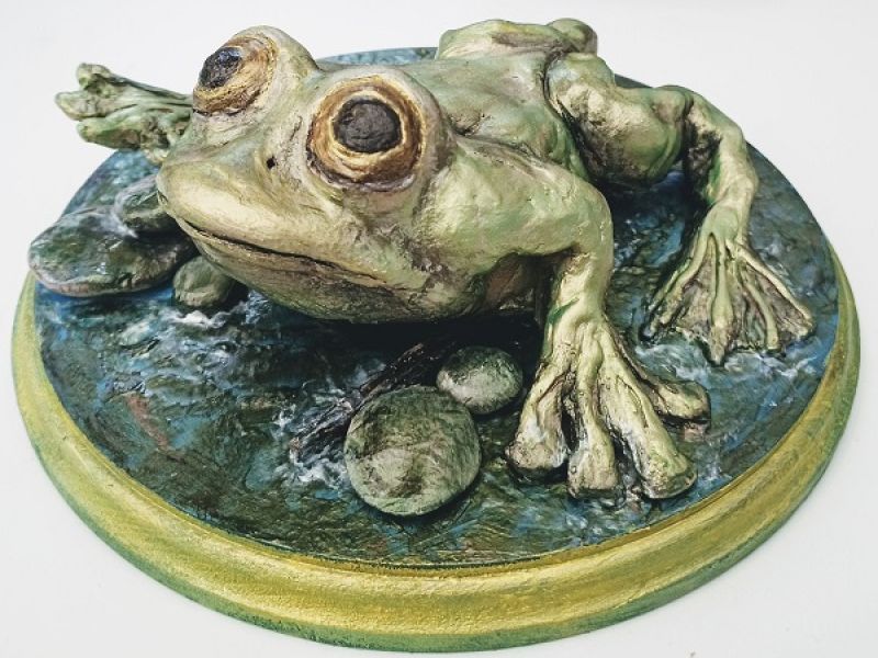 green sculpture of a frog on a plinth
